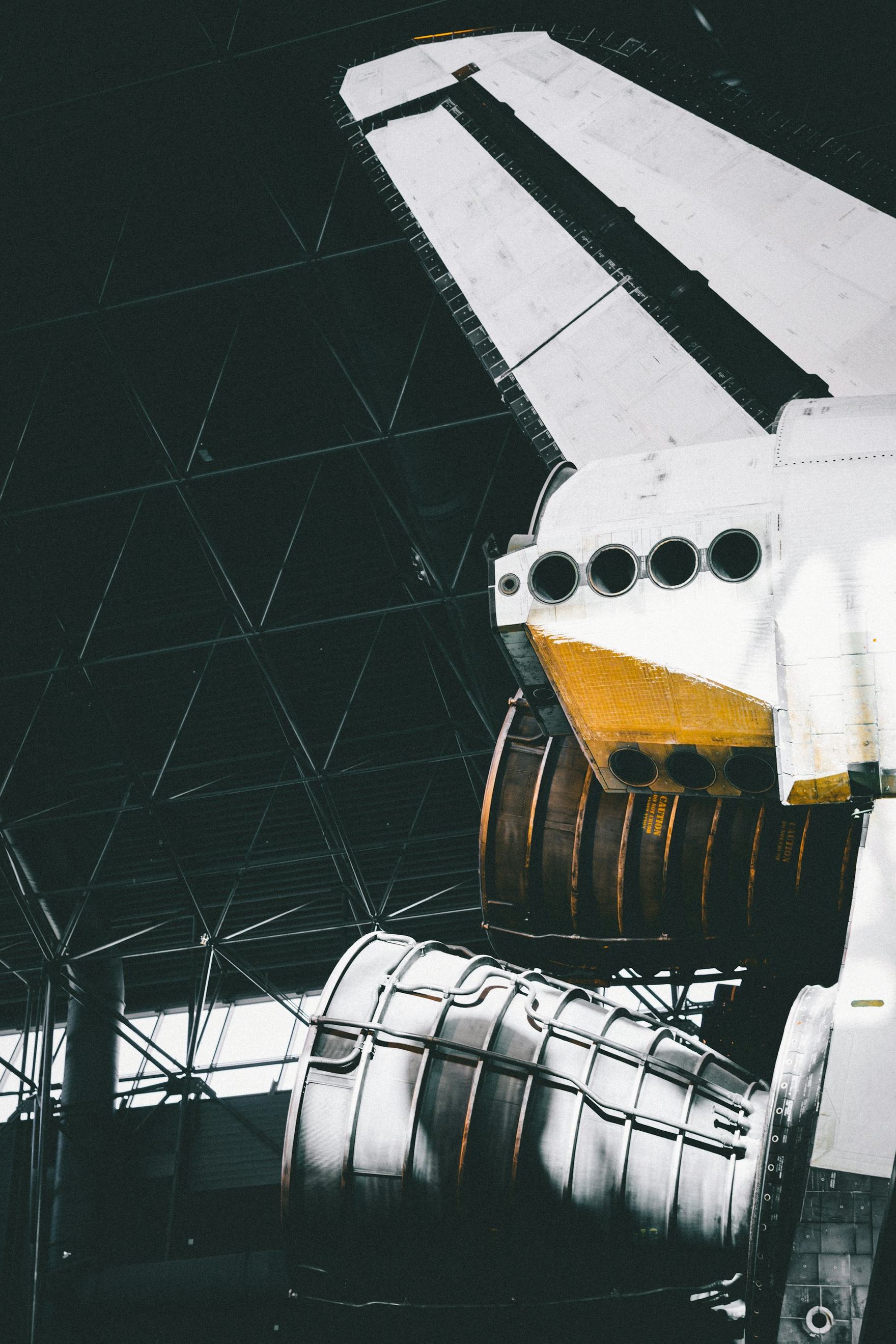 Dark silhouette of an aircraft tail and winglet against a hangar structure